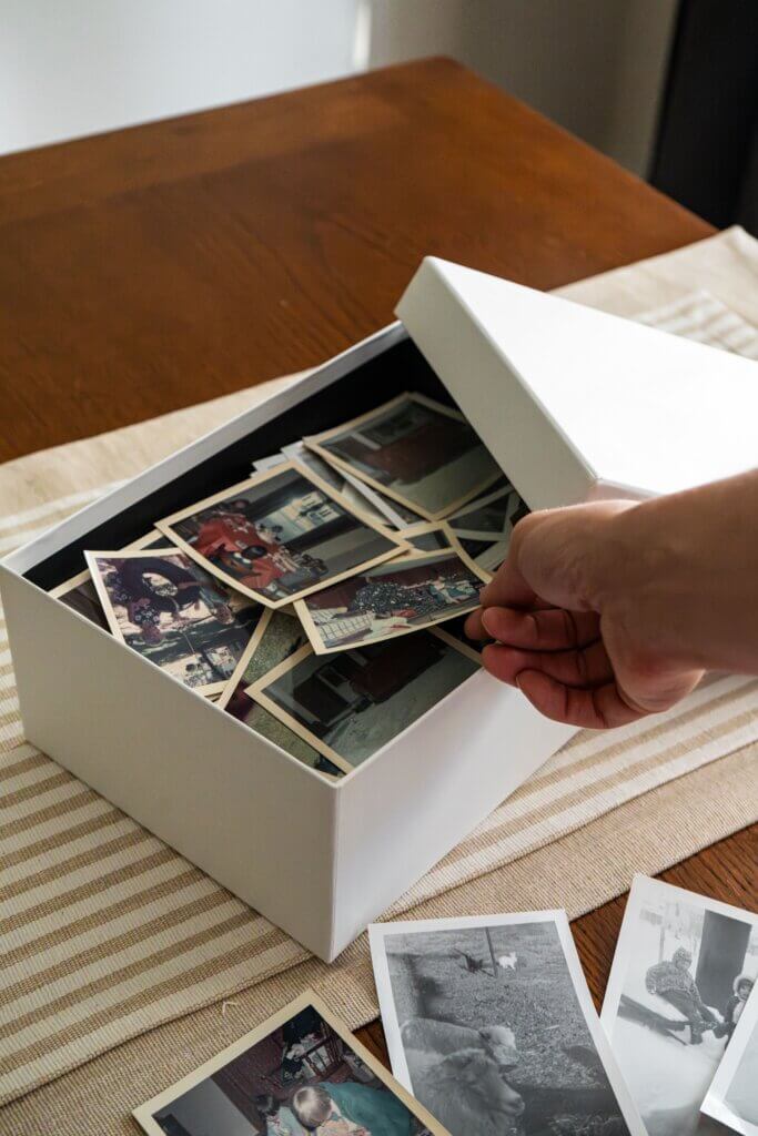 Caja con fotografías familiares antiguas, imagen que ilustra cómo la historia familiar moldea quiénes somos